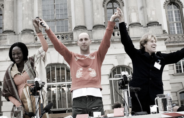 Ralf Schmerberg (center) takes a well-deserved bow with moderators Hafsat Abiola (left) and Willem Dafoe in Bebelplatz, Berlin, in ‘Problema’